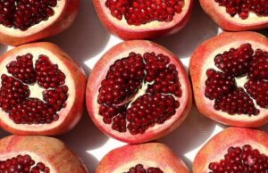 A row of three pomegranates that are cut in half.