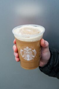 Hand holding a clear cup of Starbucks iced coffee Frappuccino.