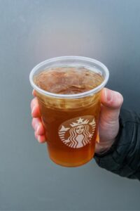 Hand holding a clear cup of Starbucks iced green tea.