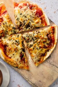 Three slices of tortilla pizza on top of a wooden cutting board.