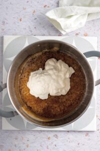 Heavy cream on top of a butter and allulose mixture in a pot.