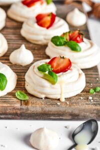 Three meringues in a row on a wooden cutting board.