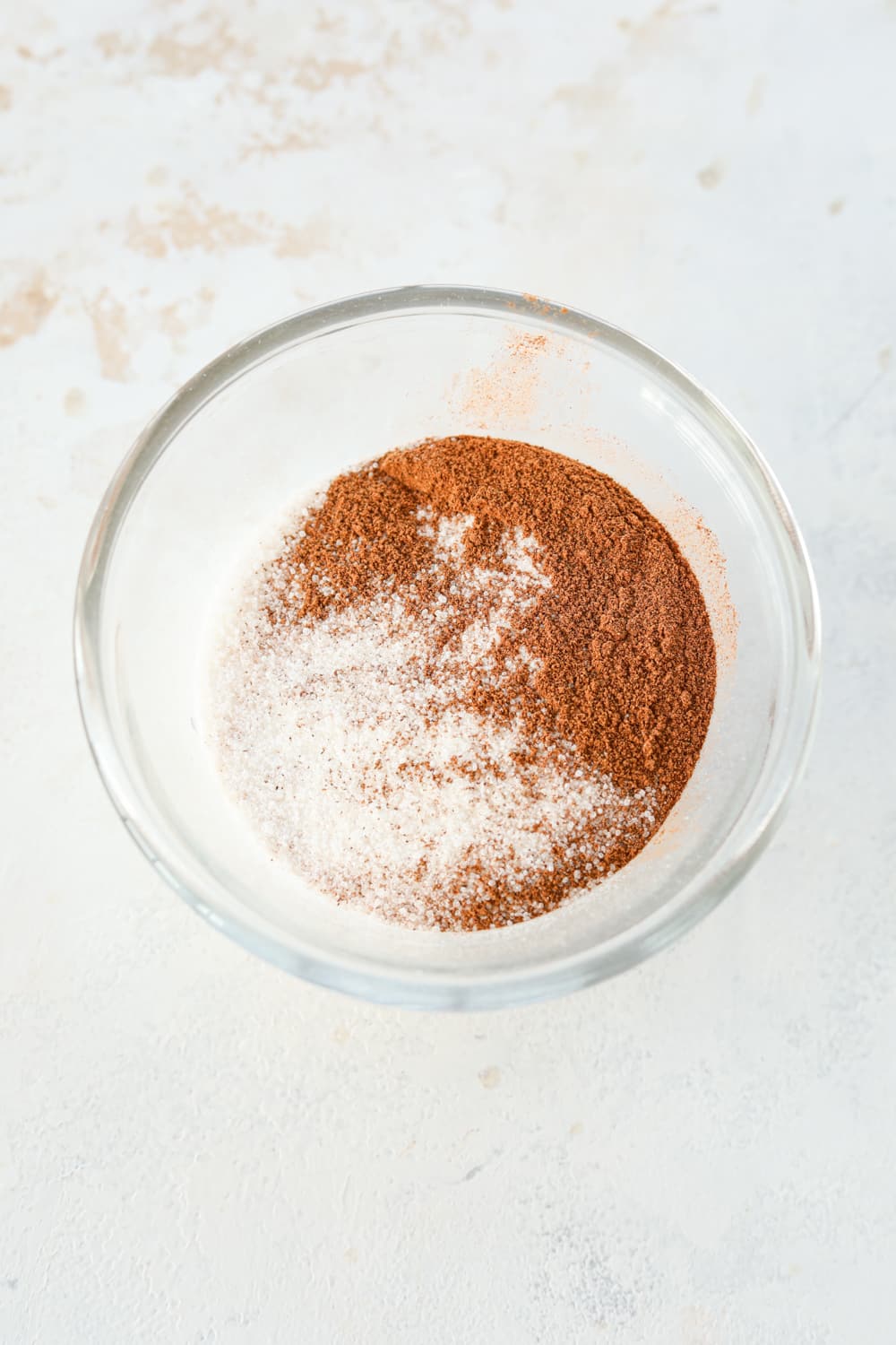 Cinnamon and sweetener unmixed in a glass bowl.
