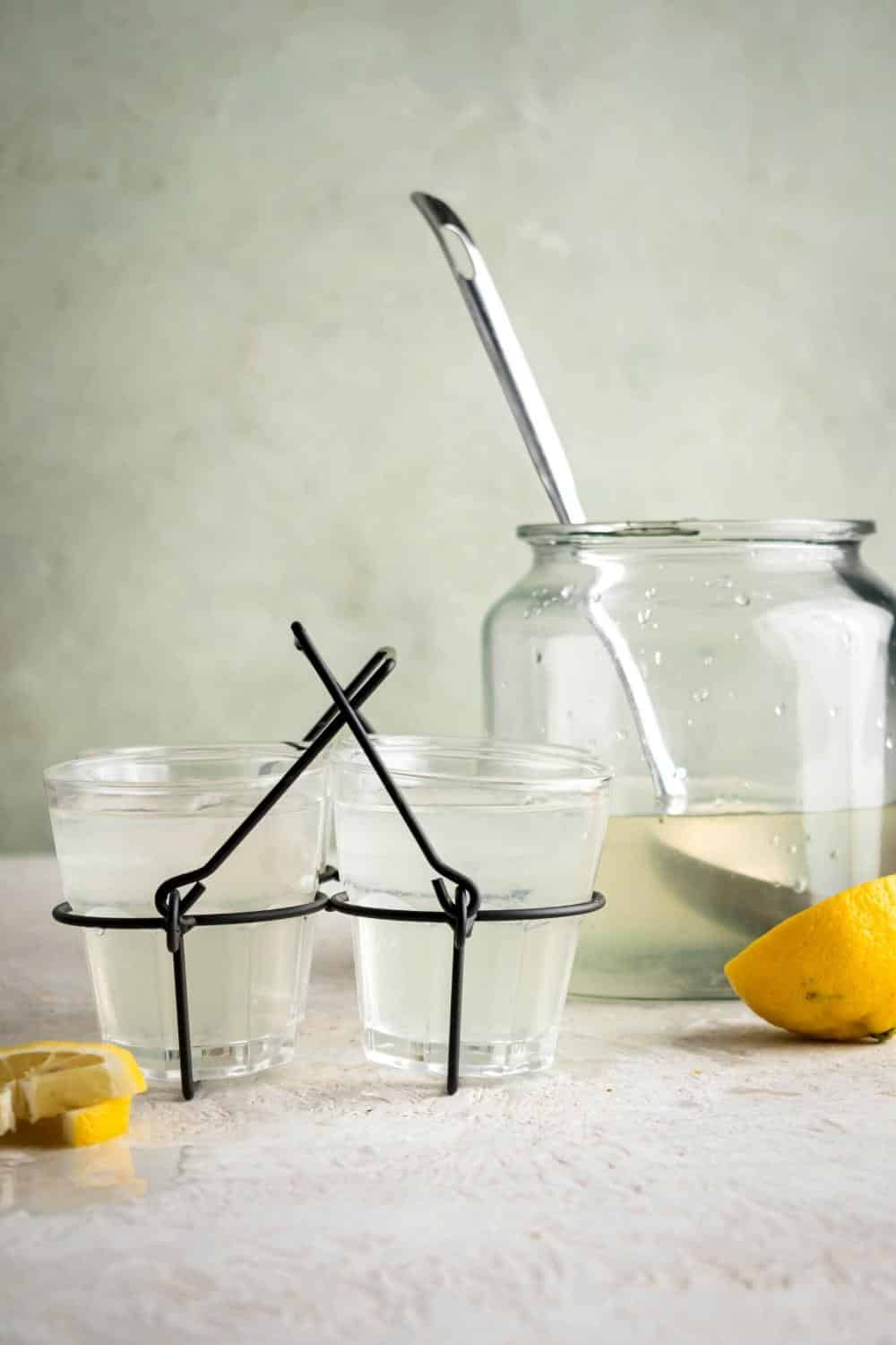 Four glasses of lemonade in a wire rack with a pitched of the lemonade behind it.