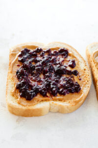 A slice of low-calorie bread with peanut butter and jelly on it.