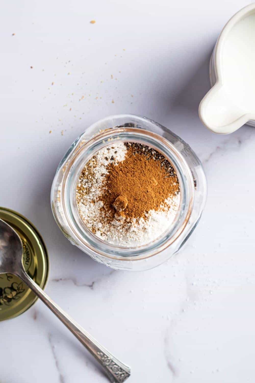 Cinnamon, erythritol, golden flaxseed, Chia seeds, almond flour, coconut flour all in a glass jar that is on a white counter.