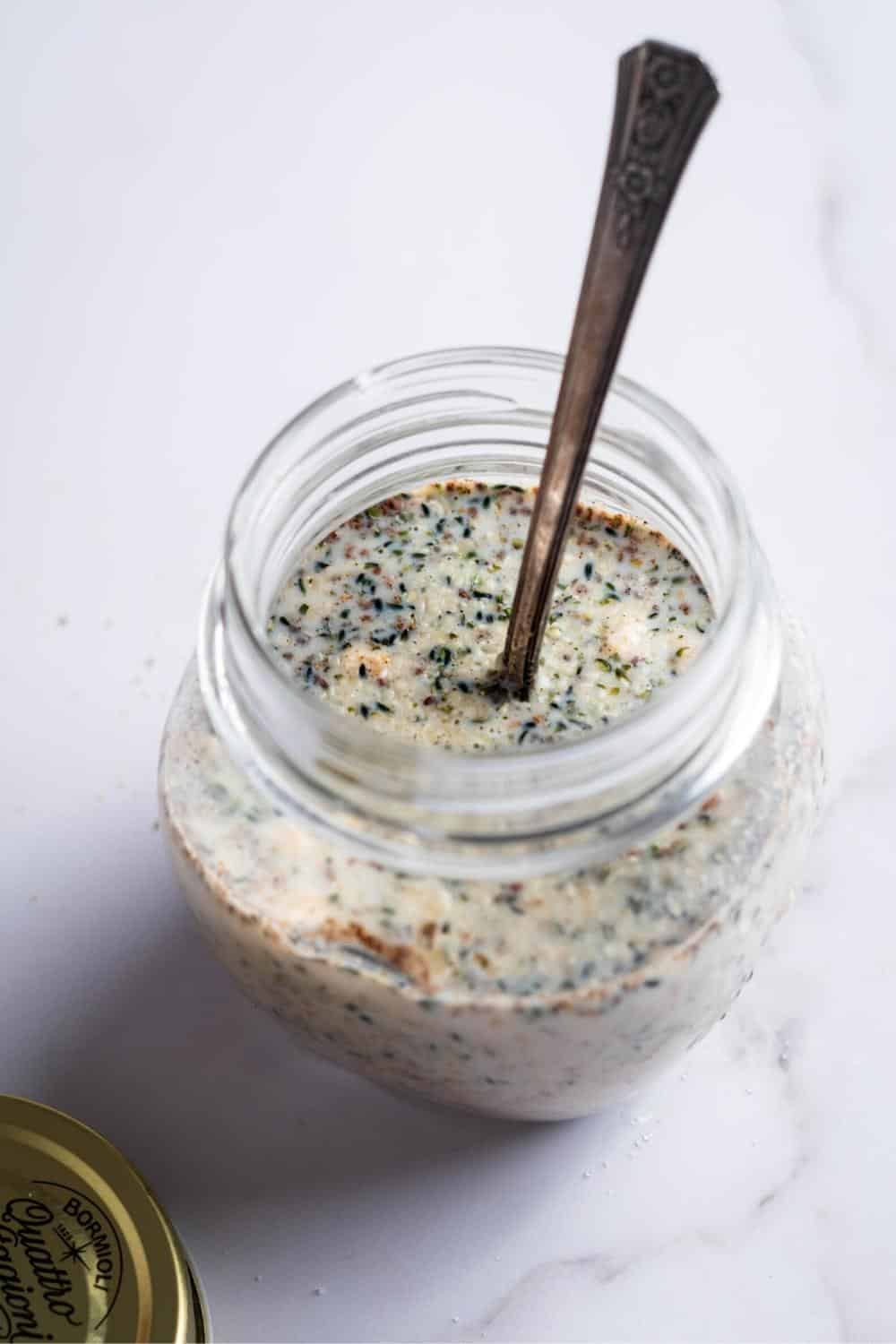 A spoon submerged in a glass jar filled with keto overnight oats