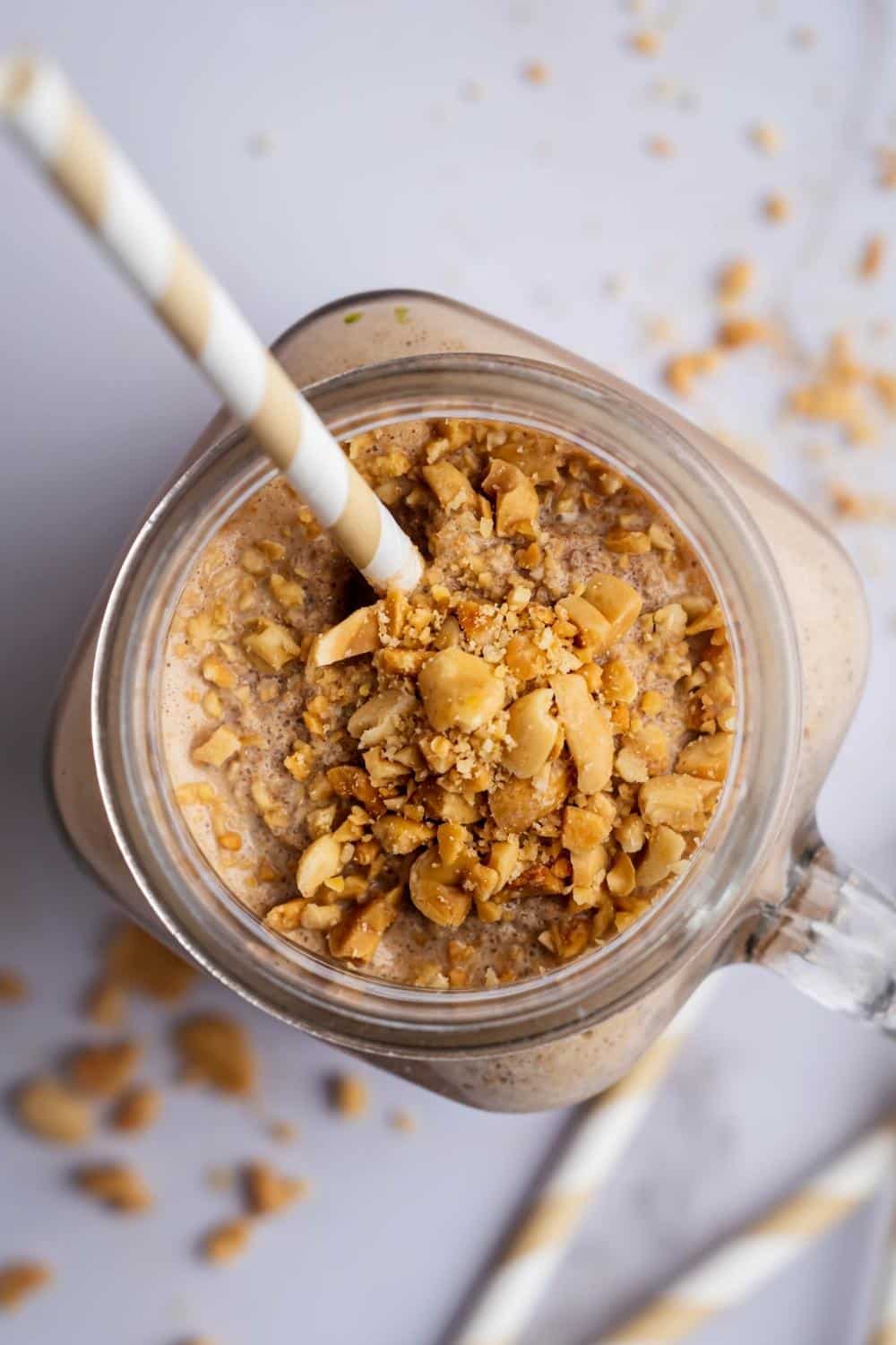 Crushed peanuts on top of a protein shake in a glass mug.