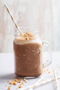 A glass mug that is filled with a keto peanut butter smoothie.