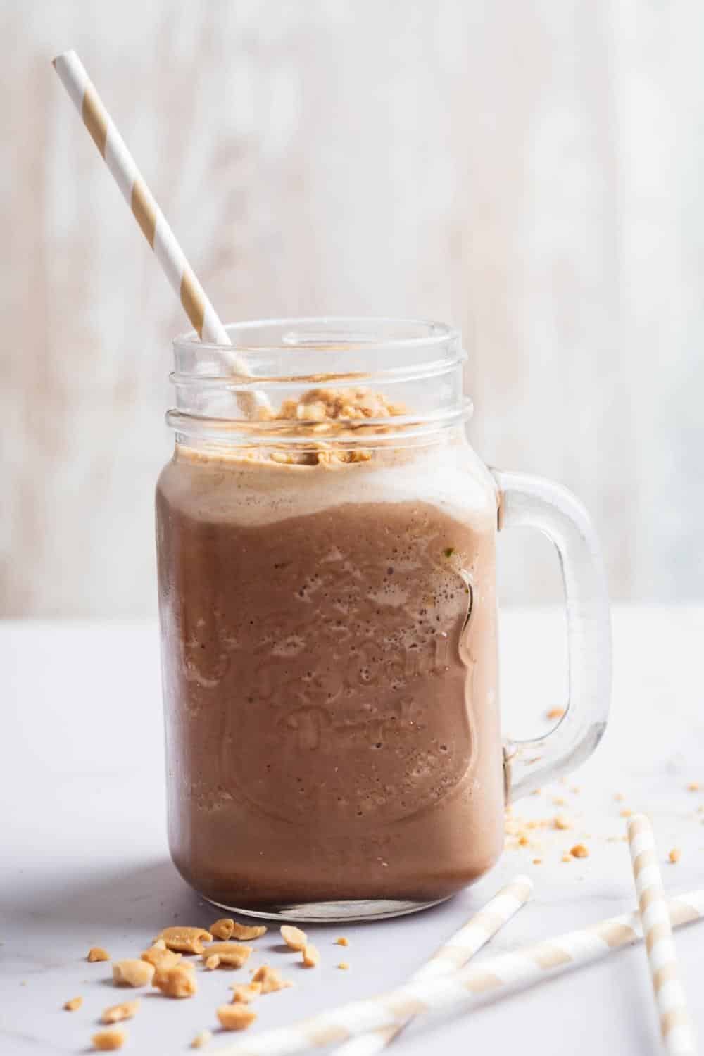 A glass mug that is filled with a keto peanut butter smoothie.