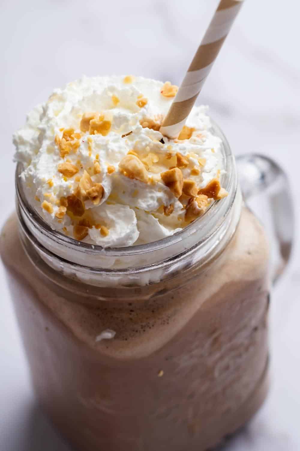 Crushed peanuts on top of whipped cream on top of a keto smoothie in a glass mug.