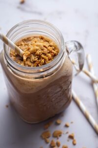 A glass mug with a keto smoothie in it with crushed peanuts on top.