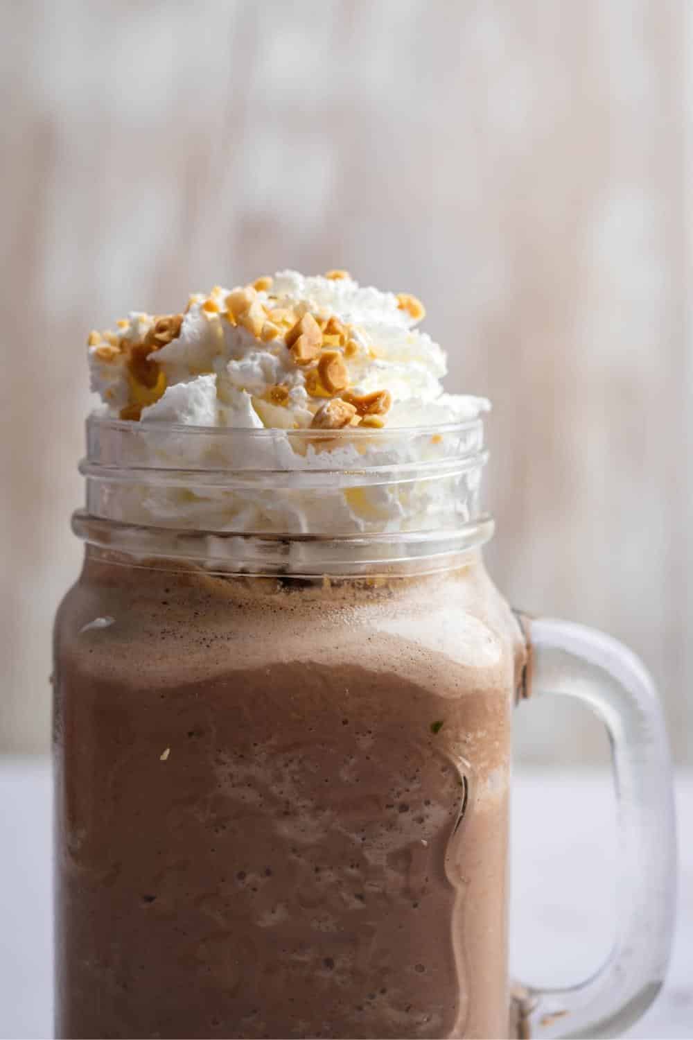 A glass mug that is filled with a keto smoothie with whipped cream on top.