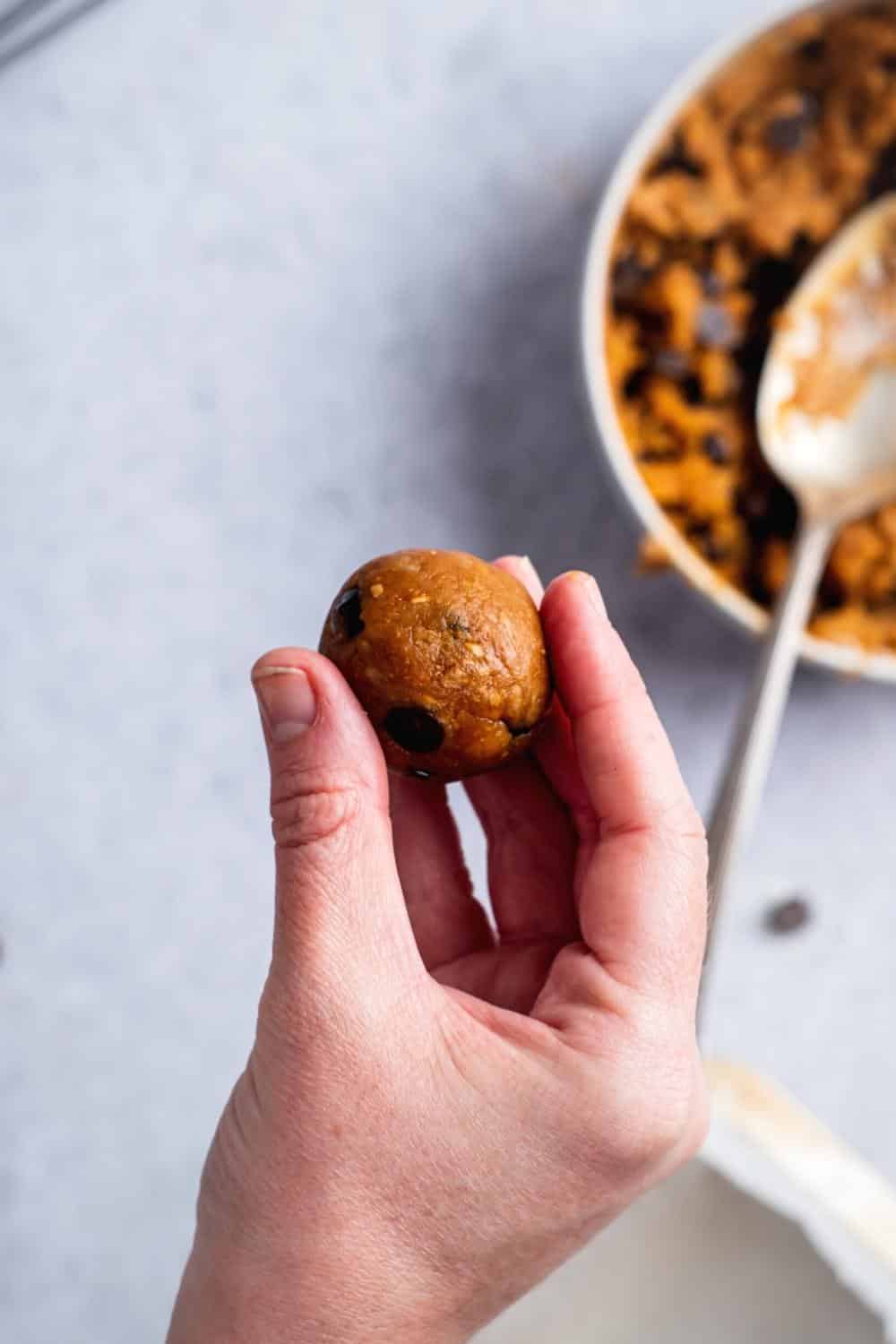A hand holding a ball of protein cookie dough.