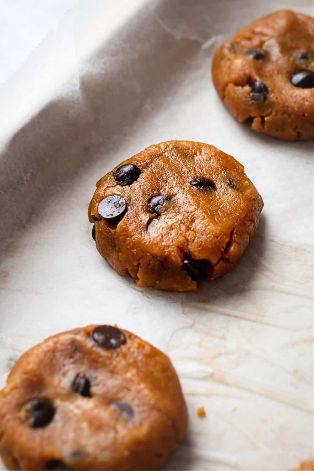 Three protein cookie dough balls that are slightly flattened,