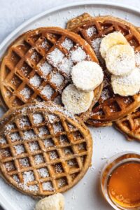 Three protein waffles overlapping one another on a white plate.