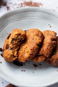 Three protein cookies leaning against one another with the front cookie with a bite out of it.