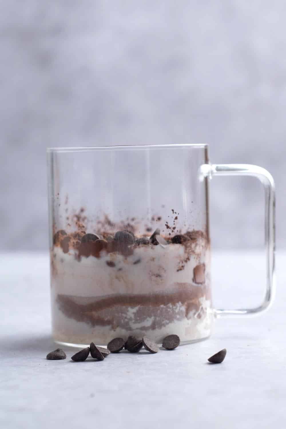A glass mug filled with chocolate protein mug cake ingredients.
