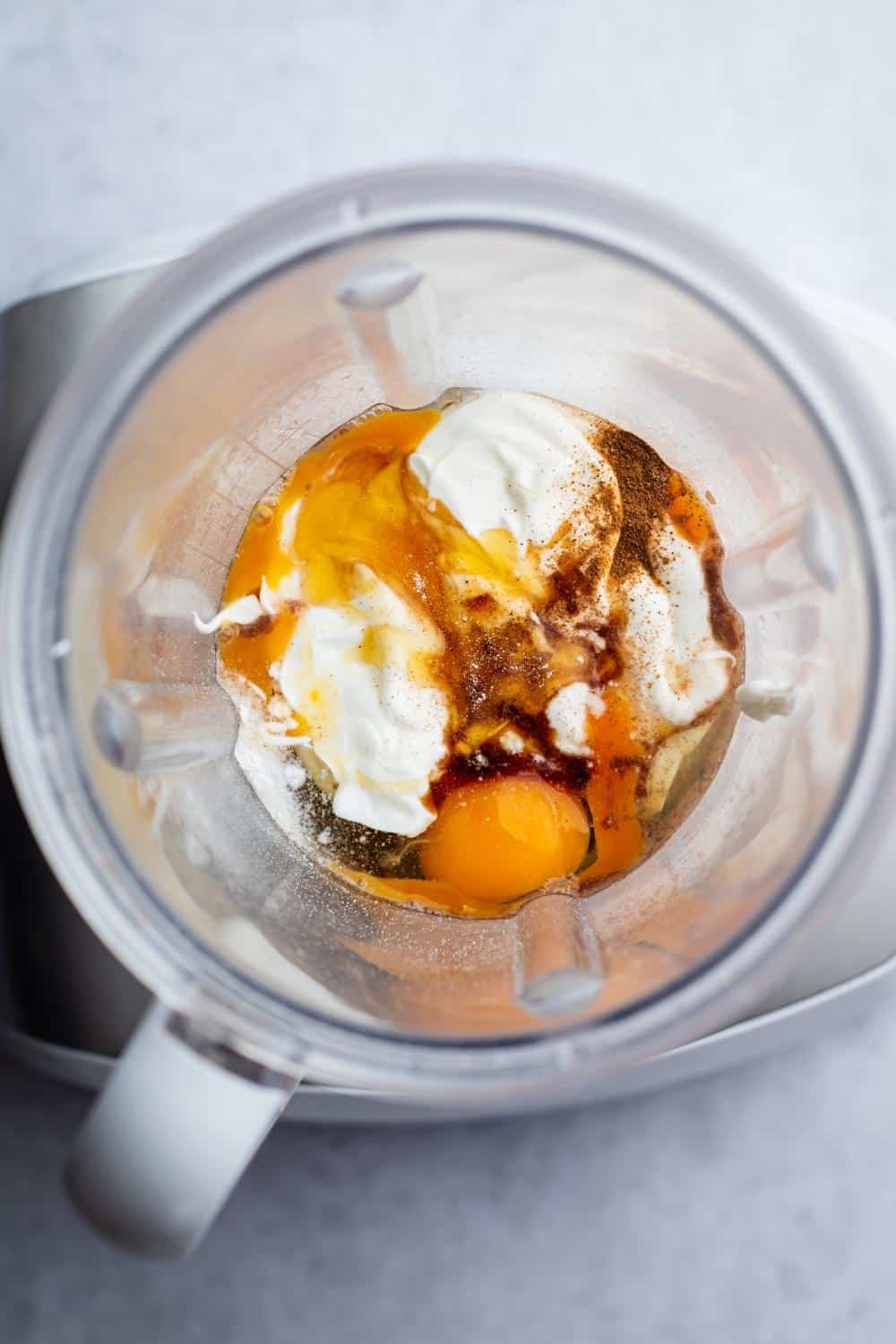 An egg, Greek yogurt, cinnamon, and milk in a blender.