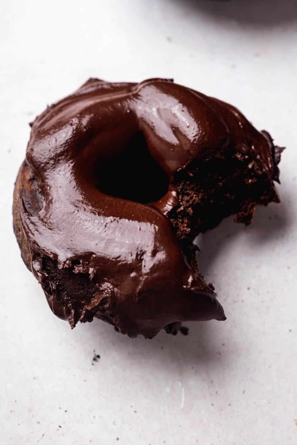 A chocolate glazed protein doughnut with a bite out of it.