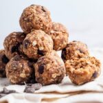 A bunch of protein balls on top of each other a tablecloth.