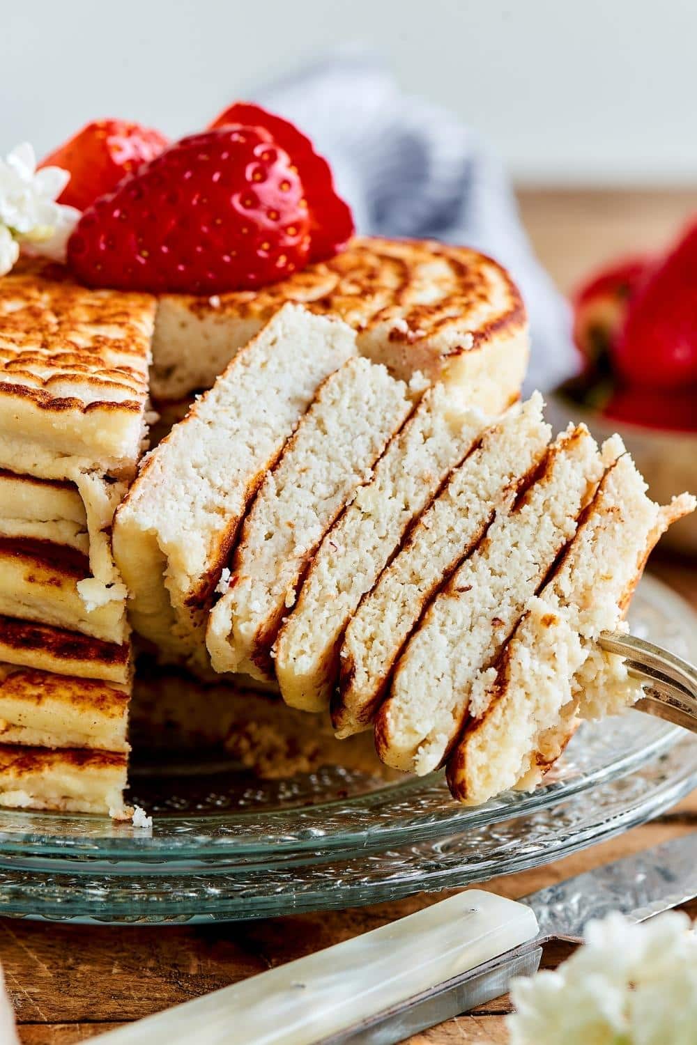 A stack of a piece six pancakes on a fork in front of the stack of pancakes.