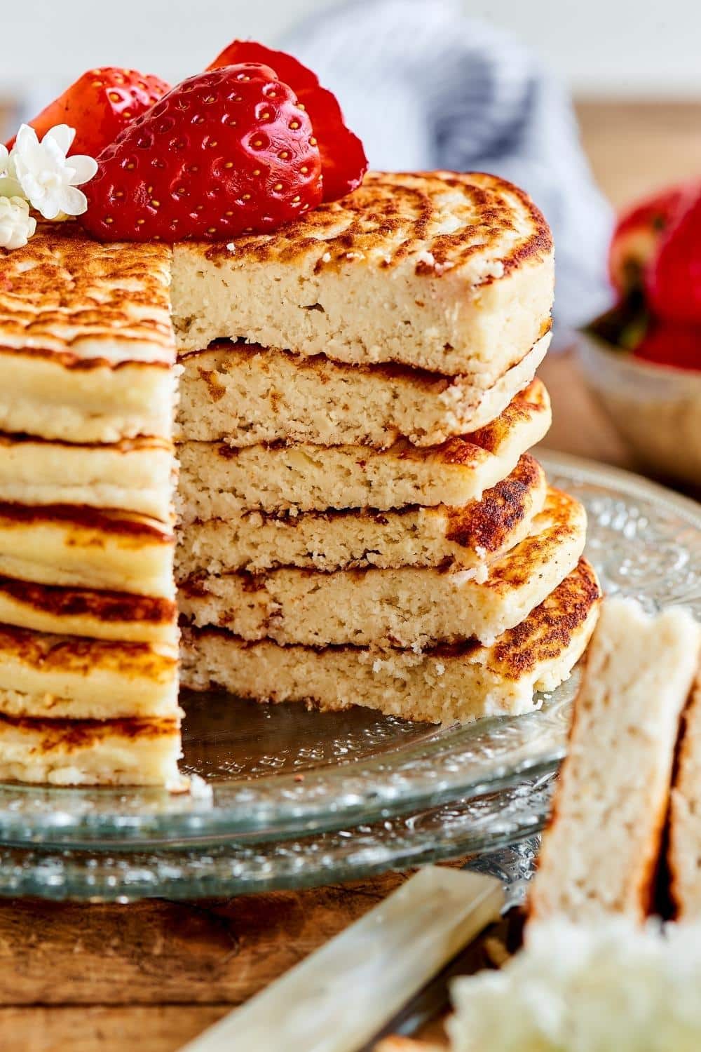 A stack of six pancakes with a slice missing out of the front.