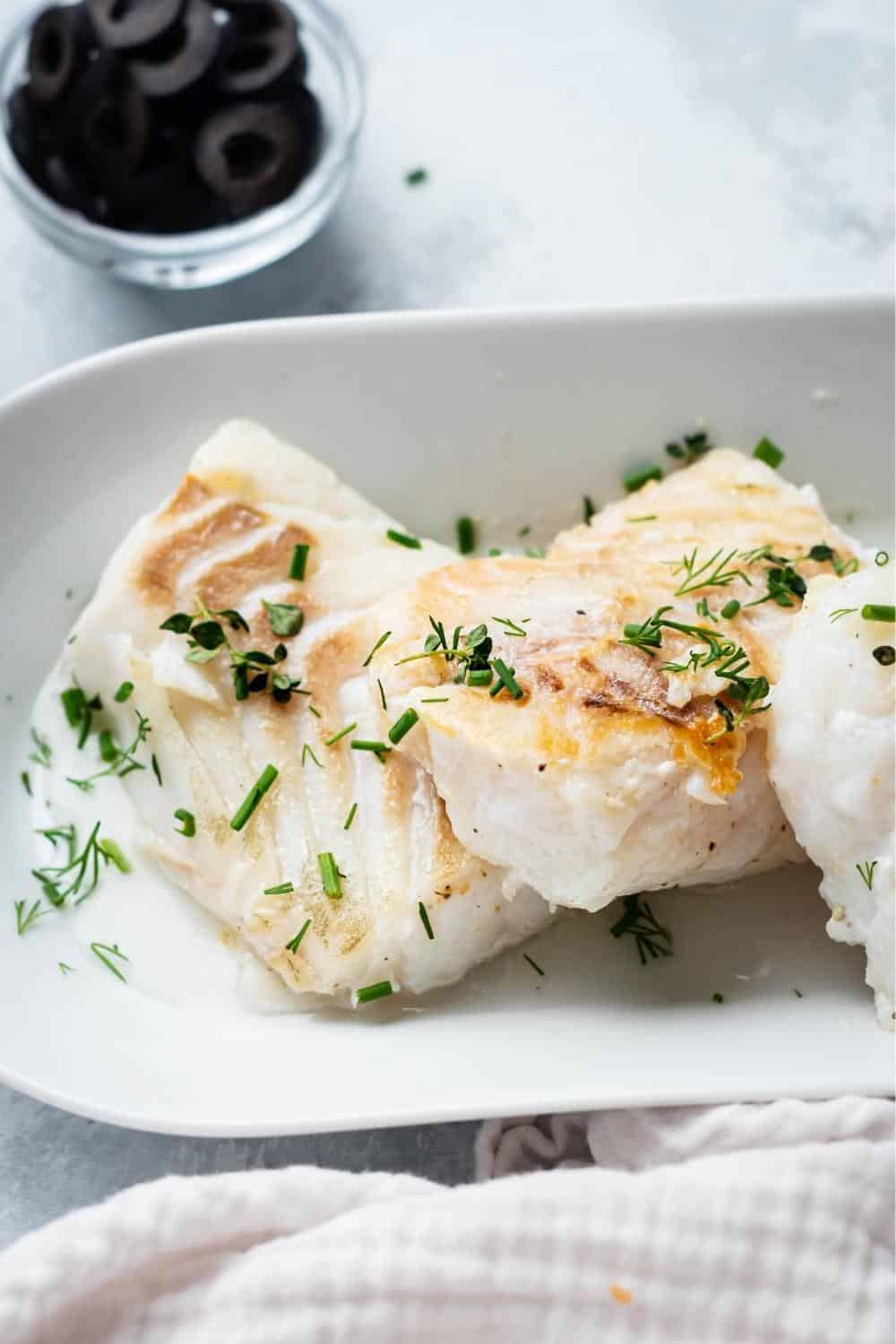 Pan seared halibut in a rectangular white dish.