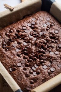 Brownies in a tray lined with parchment paper.