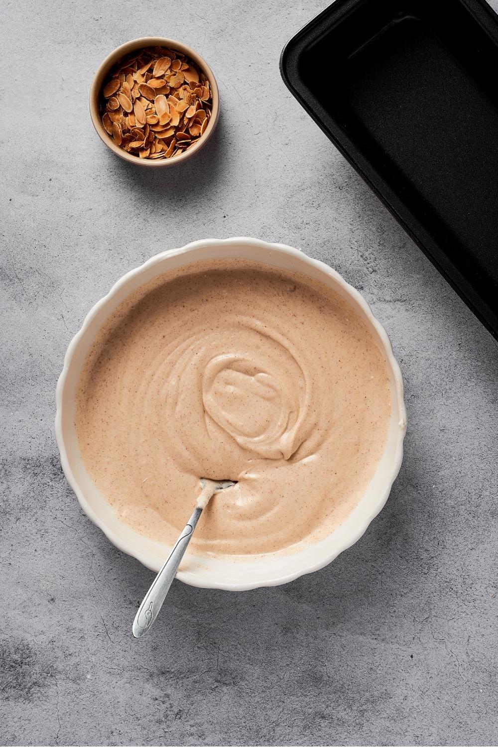 A bowl of mixed almond ice cream with a bowl of toasted almonds behind it.