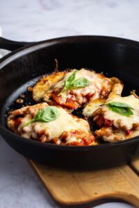 Three pieces of keto chicken parm in a black skillet.