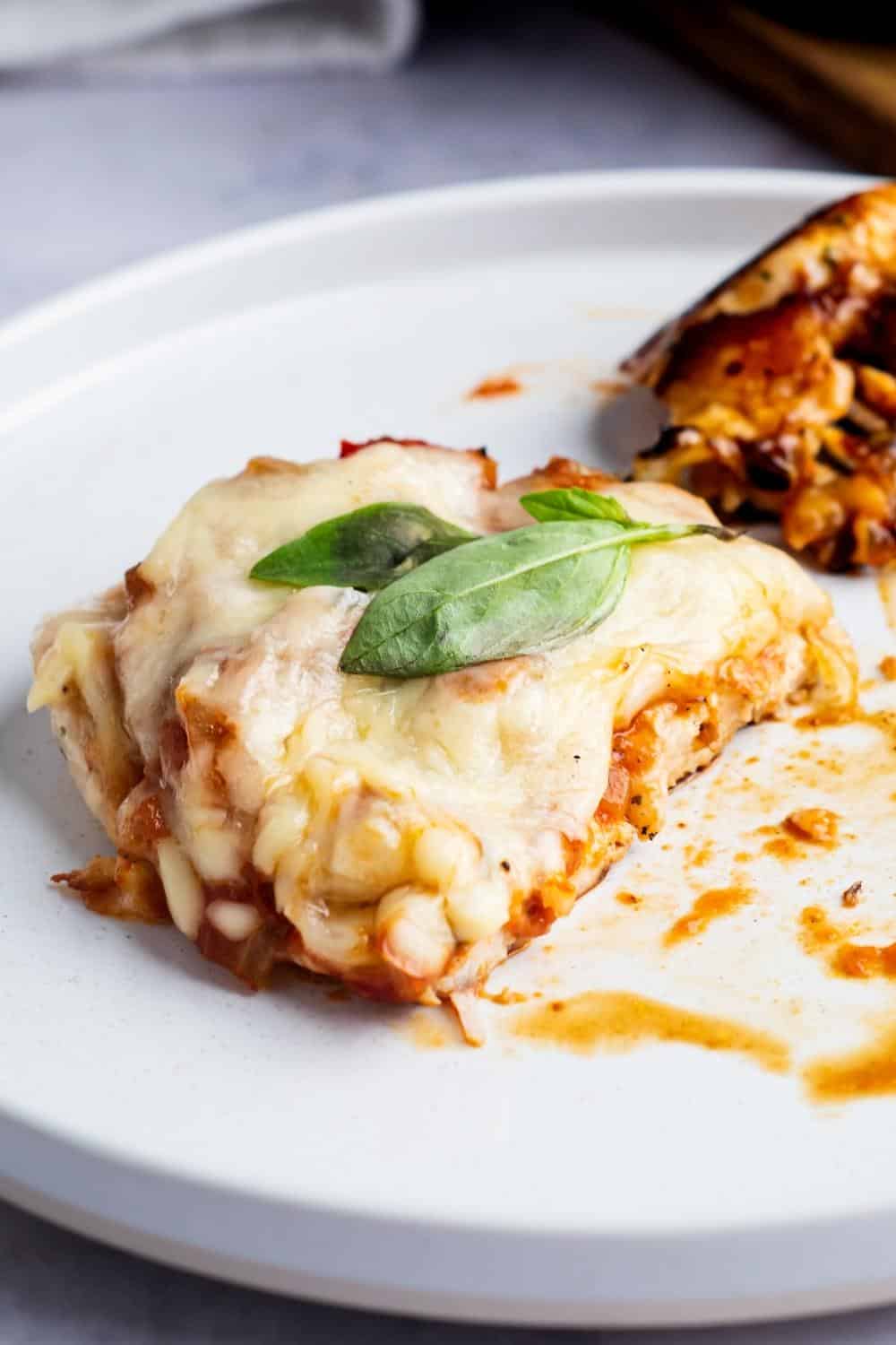 A piece of keto chicken parmesan on a white plate.