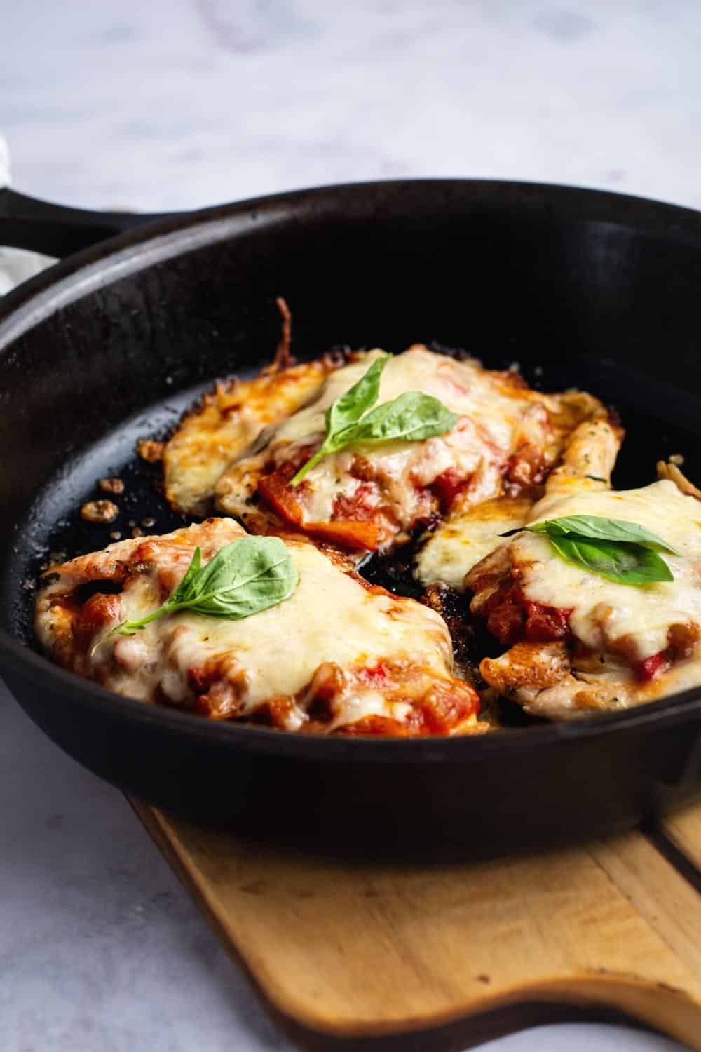 Three pieces of keto chicken parm in a black skillet.