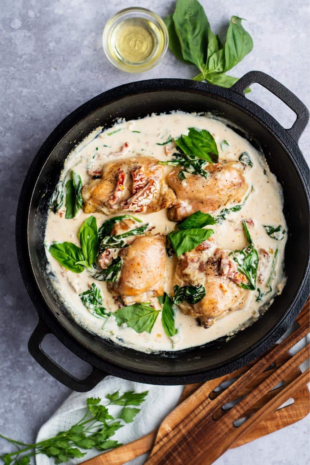 Chicken thighs, spinach, and sun dried tomatoes in a cream sauce in a pot.