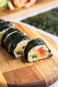 A couple of keto sushi rolls on a wooden cutting board.