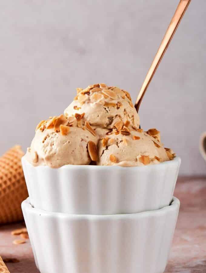 Three scoops of almond ice cream in a white bowl.