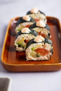 Five sushi roll pieces staggered in a line on a serving plate.