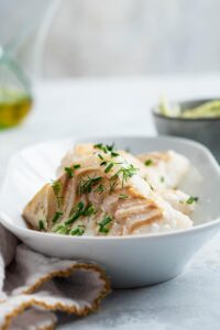 Pan seared halibut fillets an rectangular white dish.