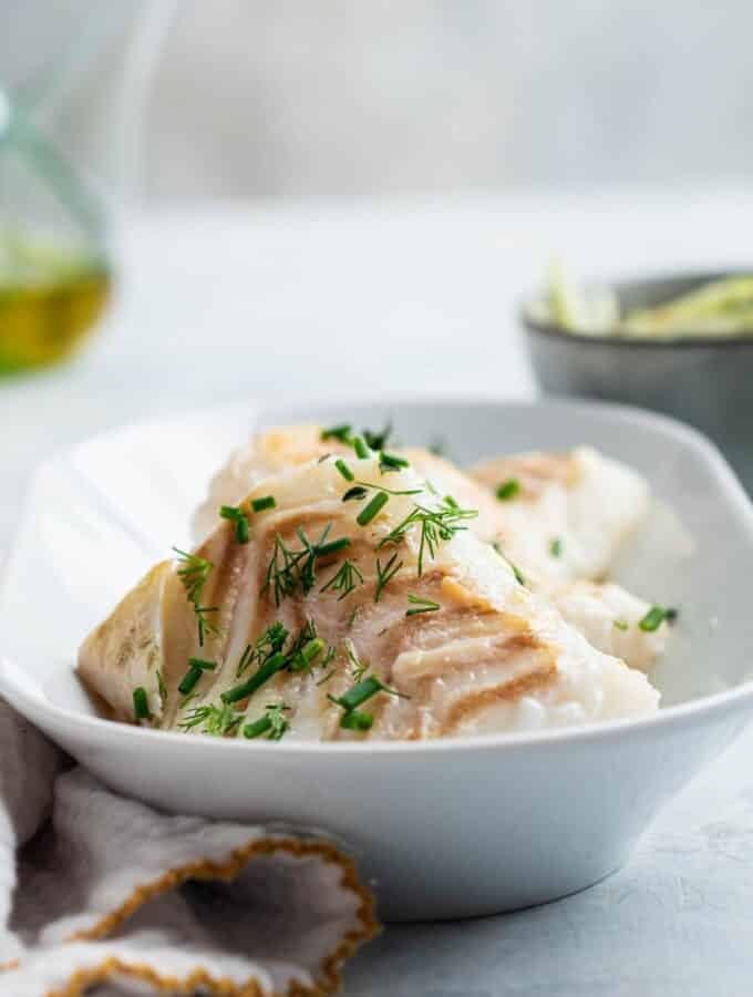 Pan seared halibut fillets an rectangular white dish.