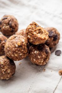A few protein balls on top of each other on a white tablecloth.