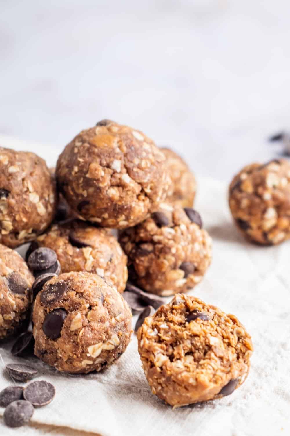 A protein ball with a bite out of the front of it with a bunch of protein bites stacked on top of each other.
