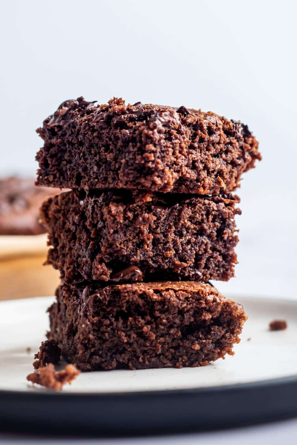 Three brownies stacked on top of one another on a white plate.