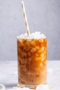 Protein coffee and ice cubes in a glass with a straw in it.