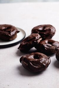 Four chocolate glazed protein donuts on a white counter.