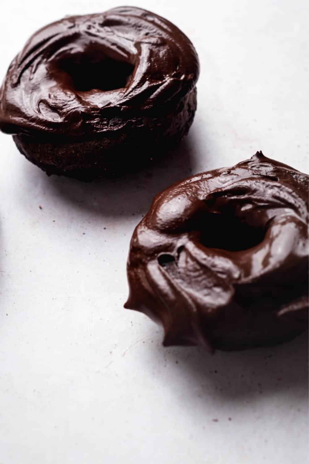 Chocolate glazed protein donuts on a white counter.
