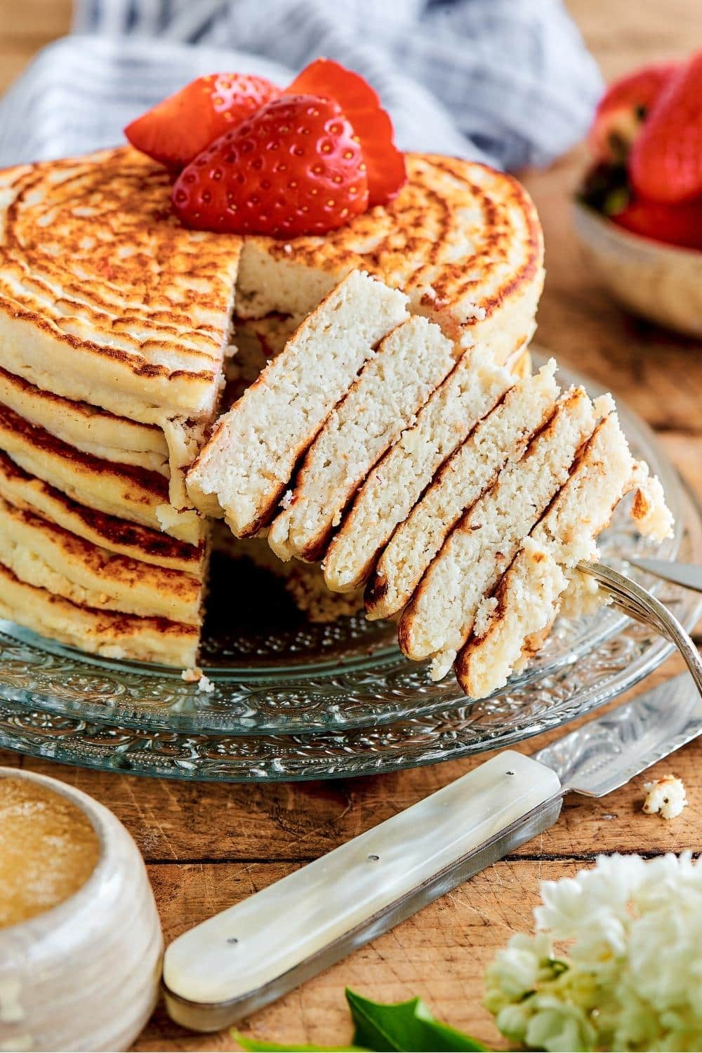 A fork with a stack of six triangles of protein pancakes on it. Directly behind it is the pancake stack.