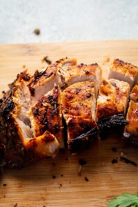 A few sliced of turkey tenderloin on a wooden cutting board.