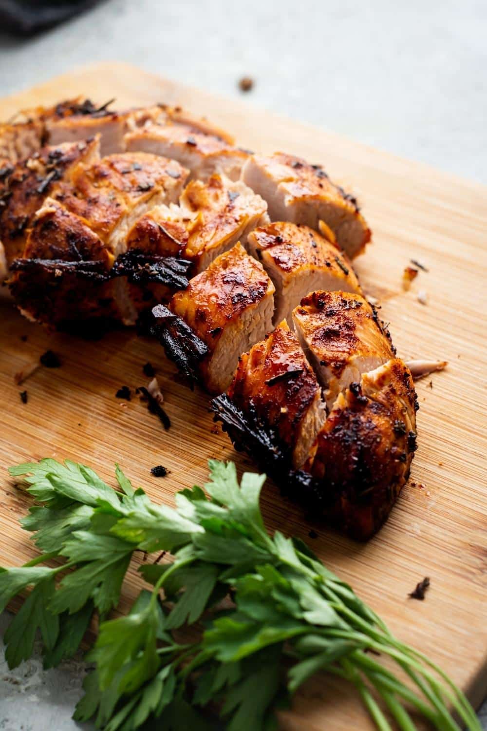 a few turkey tenderloin slices on a wooden cutting board.