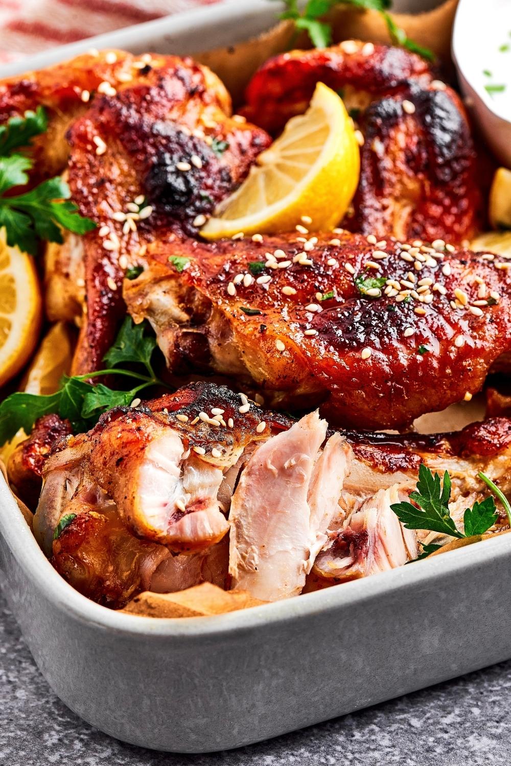 Part of a casserole dish with a picked apart turkey wing and some more turkey wings behind it.