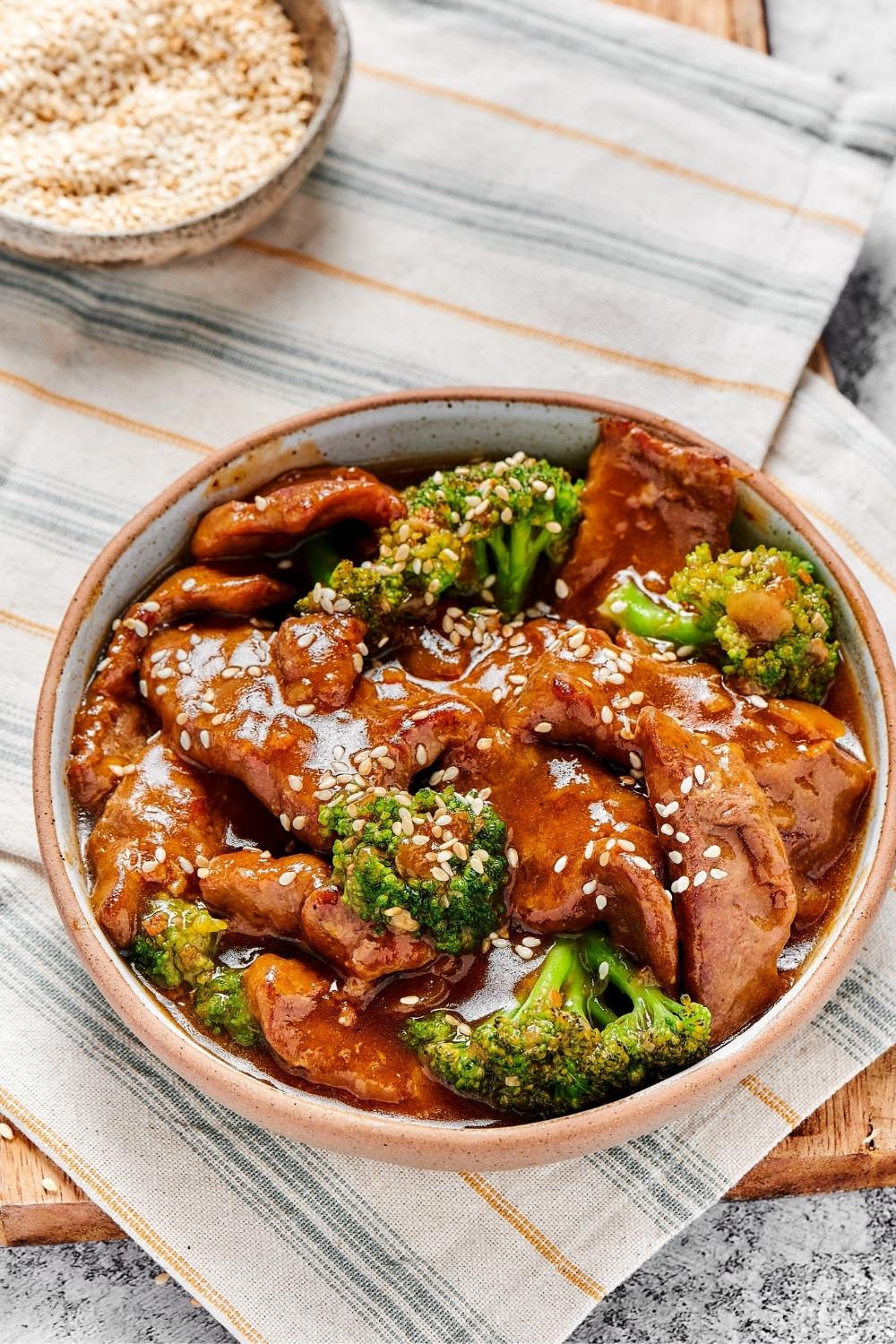 Beef and broccoli covered in stir fry sauce in a bowl on a tablelcoth.